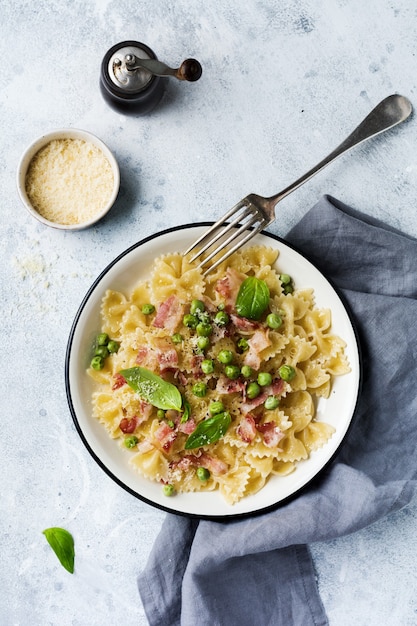 Fettuccine con pancetta e piselli e parmigiano in lamiera leggera sulla vecchia superficie di cemento grigio