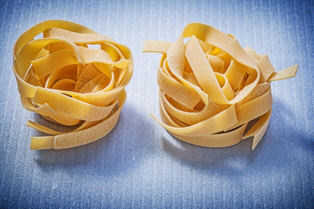 Fettuccine di pasta cruda su sfondo blu concetto di cibo e bevande