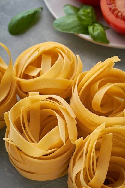 Fettuccine di pasta italiana con basilico olio d'oliva pomodoro su sfondo grigio