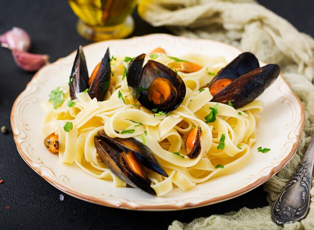 Fettuccine di pesce con cozze su sfondo nero. Cibo delicatezza mediterranea.