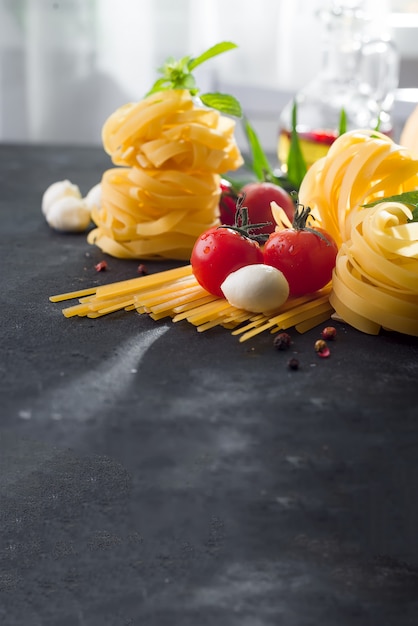 Fettuccine e spaghetti con ingredienti per cucinare la pasta sulla pietra nera