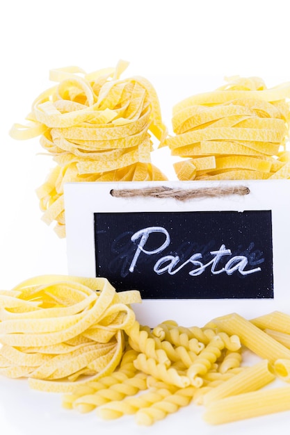 Fettuccine gialle organiche nidificano la pasta su uno sfondo bianco.