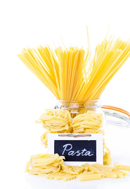 Fettuccine gialle organiche nidificano la pasta su uno sfondo bianco.