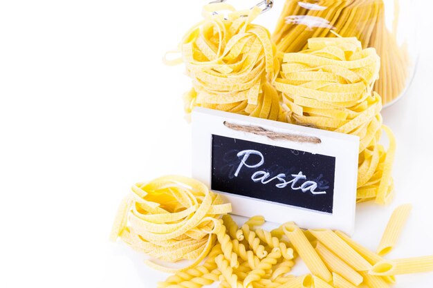 Fettuccine gialle organiche nidificano la pasta su uno sfondo bianco.