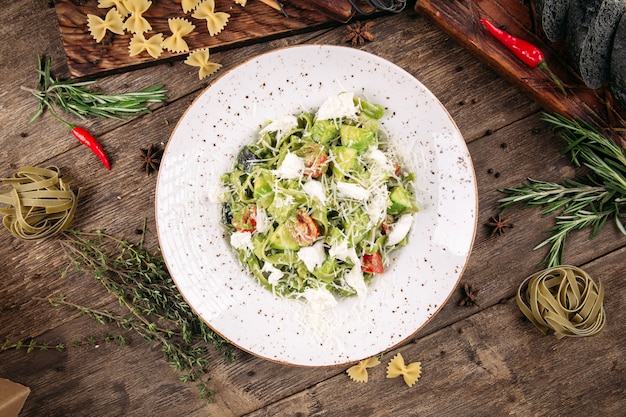 Fettuccine verdi con pomodoro e formaggio sul tavolo di legno