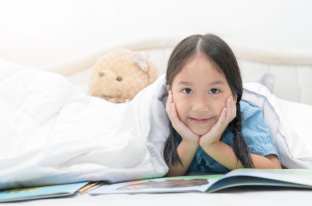 fiabe asiatiche sveglie della lettura della ragazza sveglia sul letto, concetto di istruzione