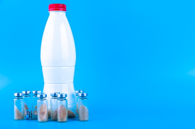 Fiale, fiale con probiotico secco, bifidobatteri e una bottiglia con latte su sfondo blu. Copia spazio.