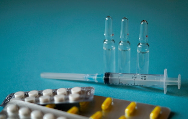 Fiale mediche, pillole e una siringa su sfondo blu