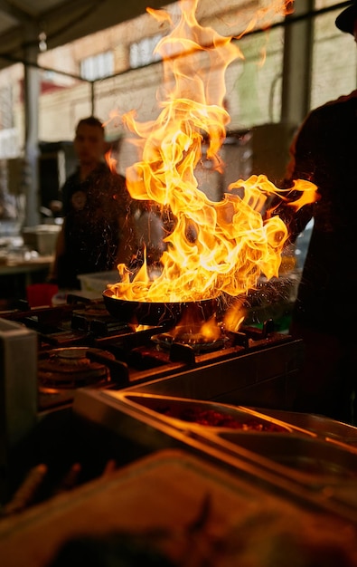 fiamma in padella Chef professionista prepara le flambe per il cibo nella cucina del ristorante