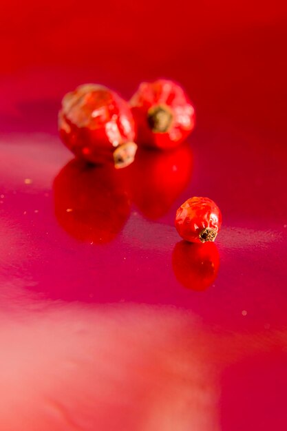 Fianchi secchi di rosa canina su sfondo rosso