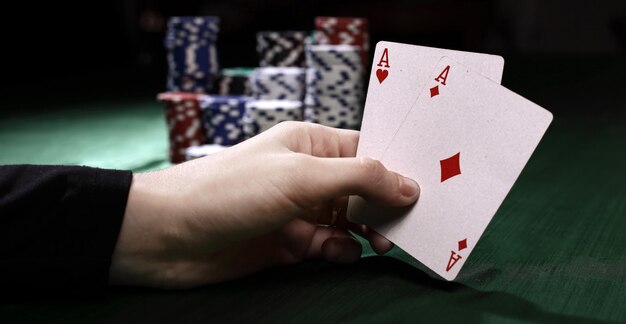 Fiches del casinò del primo piano e carte da gioco nella mano dei giocatori