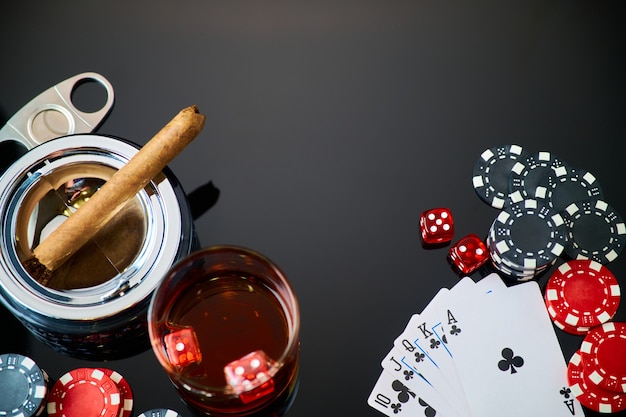 Fiches del casinò giocando a carte bicchiere di whisky e dadi su sfondo riflettente scuro dark