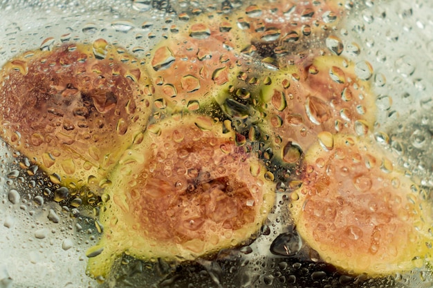 Fichi freschi e metà di fico su un piatto sotto un film con gocce d'acqua Sfondo scuro closeup vista dall'alto