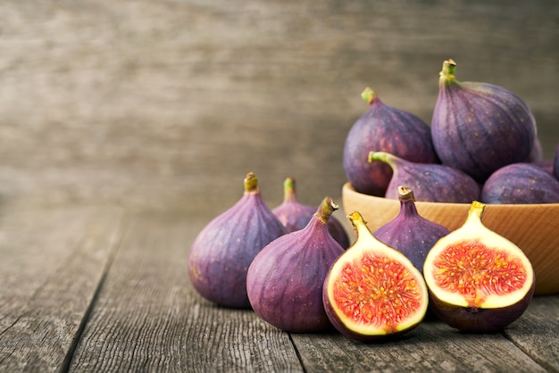 Fichi freschi in una ciotola di legno su un tavolo rustico.