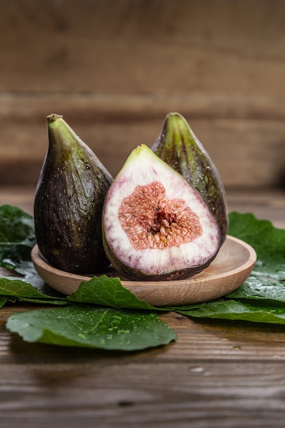 Fichi freschi sul piatto di legno con foglie di fico