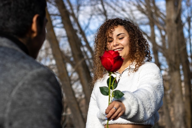 Fidanzata che regala una rosa al suo fidanzato Ragazza che regala una rosa al suo fidanzato latino il giorno di San Valentino Concetto di coppia che si scambia un regalo di San Valentino