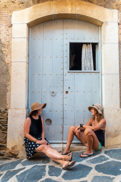 Fidanzate in estate che si godono le vacanze. Ragazze caucasiche con cappelli di paglia sorridenti sedute accanto a una porta godendosi il caldo durante le vacanze