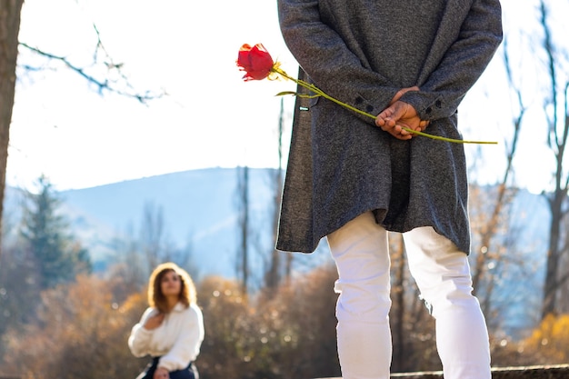 Fidanzato che nasconde una rosa a sorpresa per la sua ragazza Uomo latino che nasconde una rosa per il suo fidanzato il giorno di San Valentino