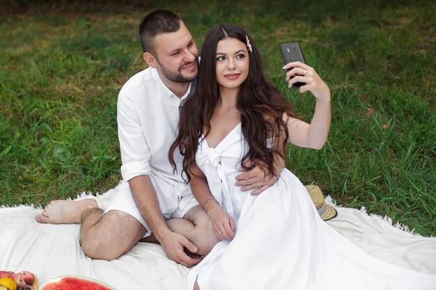 Fidanzato e ragazza che prendono selfie al picnic.