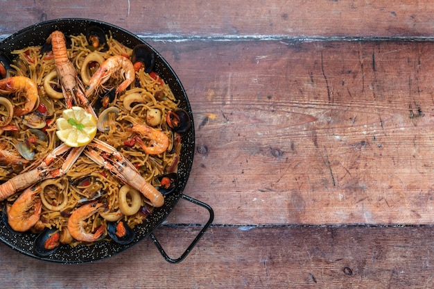 Fideua di frutti di mare su sfondo di legno, vista dall'alto