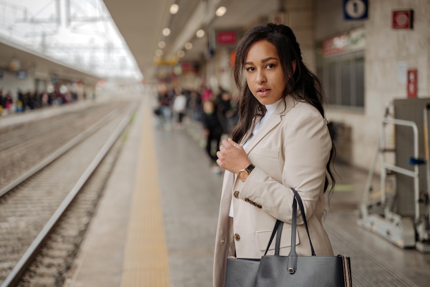 Fiduciosa donna d'affari di successo guardando la fotocamera in piedi alla stazione ferroviaria, copia spazio