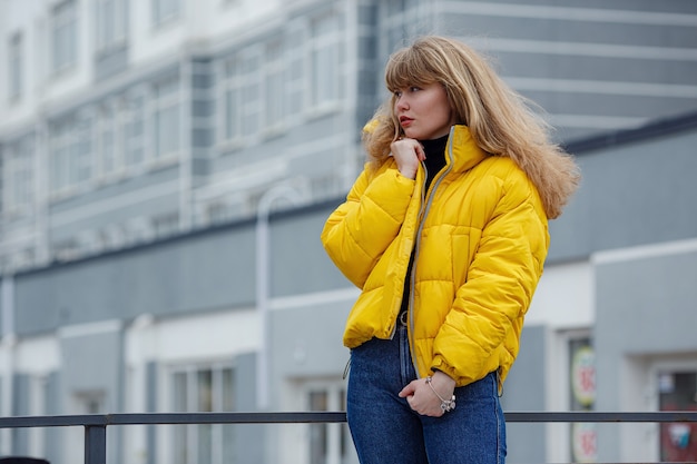 Fiduciosa felice bella giovane donna hipster che indossa giacca gialla in piedi sulla strada della città city