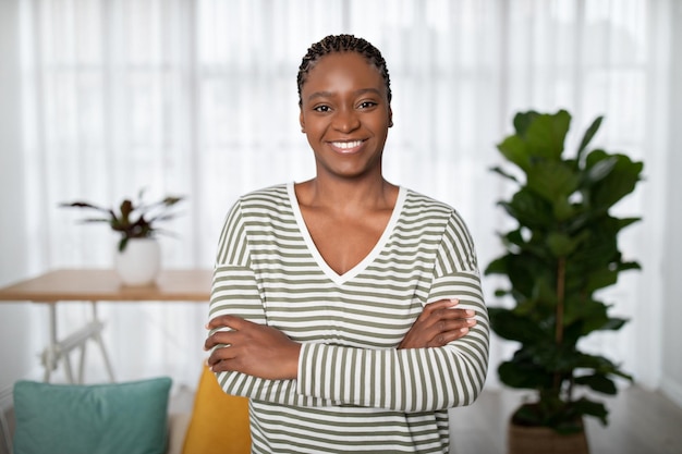 Fiduciosa giovane donna afroamericana positiva che posa a casa