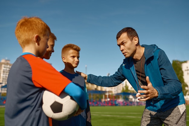 Fiducioso allenatore di calcio che incoraggia la giovane squadra di calcio