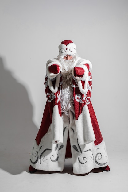 fiducioso Babbo Natale in costume tradizionale rosso e bianco e cappello con barba lunga bianca.