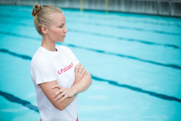 Fiducioso bagnino femminile in piedi a bordo piscina