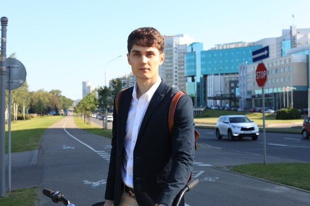 Fiducioso giovane uomo d'affari che cammina con la bicicletta per strada in città.