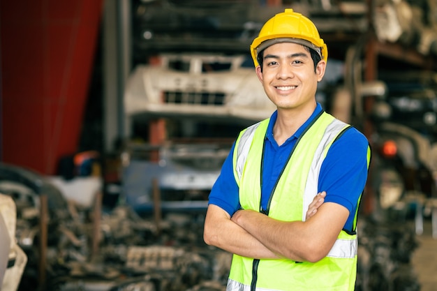 Fiducioso ingegnere maschio asiatico lavoratore in piedi braccio incrociato sorriso felice per divertirsi a lavorare in fabbrica