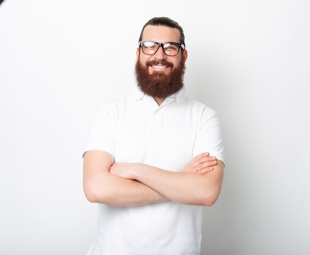 Fiducioso uomo barbuto con gli occhiali sta sorridendo alla telecamera.