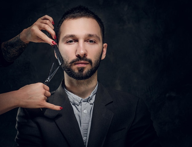 Fiducioso uomo d'affari elegante riceve una cura della barba dalla donna con una bella manicure.