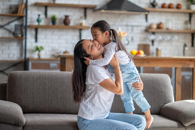 Figlia affettuosa che bacia sua madre sulla guancia