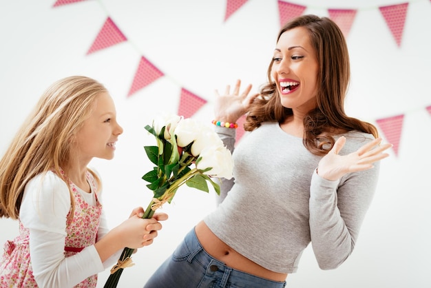 Figlia carina che dà a sua madre un bouquet di rose bianche per la festa della mamma.