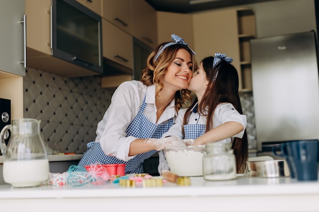 Figlia che bacia sua madre durante la cottura insieme in cucina.