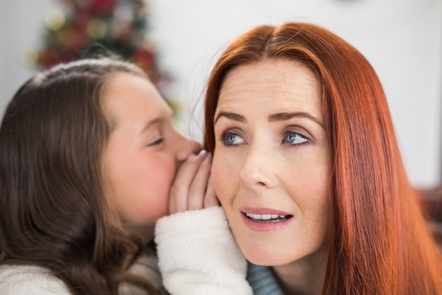 Figlia che dice a sua madre un segreto di Natale