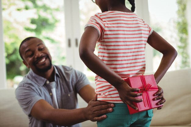 Figlia che nasconde un regalo alle spalle per suo padre