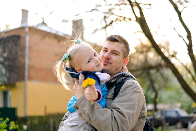 Figlia con fiori gialli sulle braccia di papà. Festa del papà. Papà con bambino.