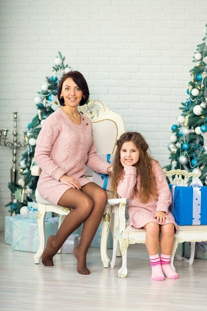 Figlia della madre e del bambino della famiglia Appy sulla mattina di natale all'albero di Natale con i regali.