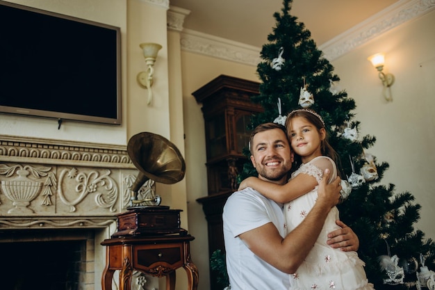 Figlia divertente che si siede sulla spalla del padre vicino all'albero di Natale a casa