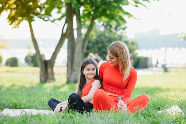 Figlia e madre carina e piccola fanno esercizi, fitness, yoga nel parco mattutino