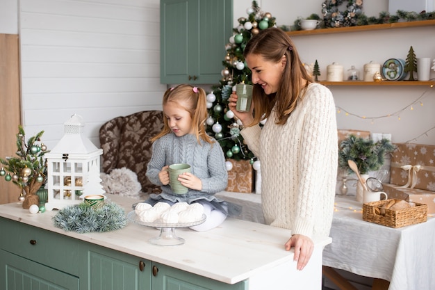 Figlia e madre con le tazze di tè nella cucina di Natale a casa.