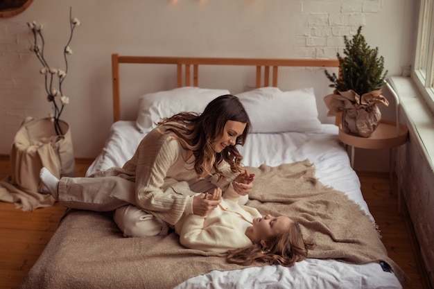 Figlia e madre di famiglia felici si divertono a casa sul letto