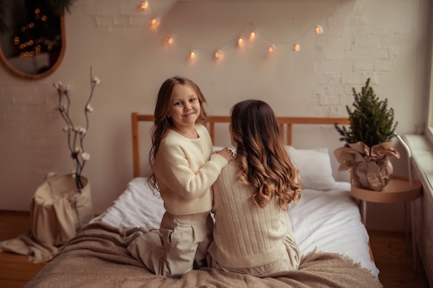 Figlia e madre di famiglia felici si divertono a casa sul letto