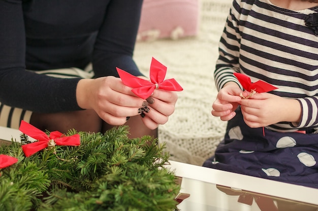 Figlia e madre fanno una ghirlanda natalizia.