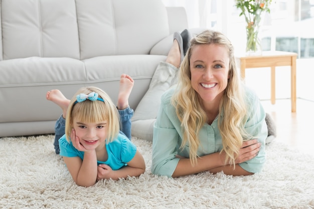 Figlia e madre sorridenti che mettono sul pavimento