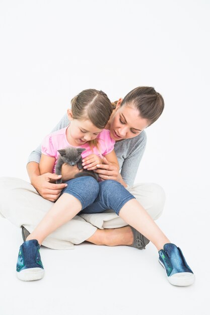 Figlia e madre sveglie che si siedono insieme con il gattino dell&#39;animale domestico