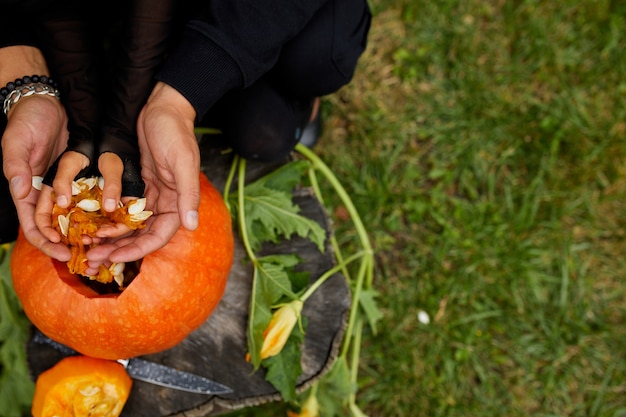 Figlia e padre mani che tira semi e materiale fibroso da una zucca prima di scolpire per Halloween. Prepara Jack o'Lantern.